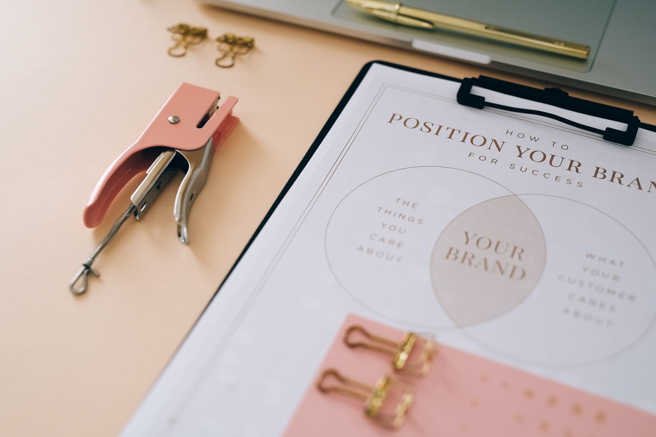 A pink stapler and a branded document sitting on a desk, highlighting a chic office arrangement.